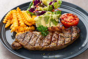 Grilled Sirloin Beef Steak with french fries and salads. Serve on Black Plate. Negative Space.