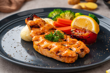 Grilled salmon fillets with mentai sauce and mash potato plating on black plate with negative space for text.