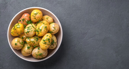 Boiled potatoes with dill and butter close-up on a dark background. Side view, horizontal