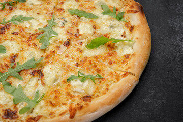 Four cheese pizza quattro fromaggi with arugula leaves on a wooden board on gray concrete horizontal