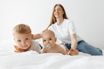 loving family. Mother her newborn daughter and little son play and hug in a bright sunny bedroom on the bed, spend time at home. moments of sensitivity