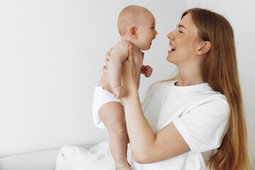 joyful mother with a cute little baby in her arms, Home portrait of a newborn with mother on the bed