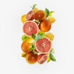Flying various citrus fruits setting with green leaves at white background. Grapefruit, lemon, orange and lime flying in the air. Levitation. Healthy food concept.