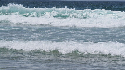 Olas marinas pequeñas rompiendo con espuma blanca.