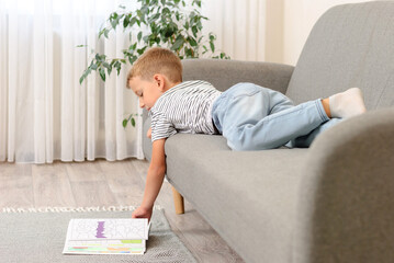 boy leafing through a book lying on the couch