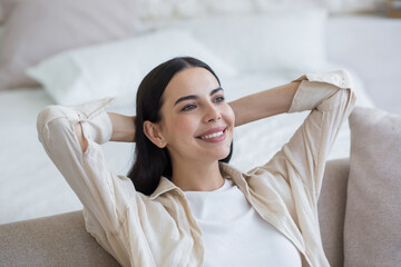 Close-up photo portrait of a young woman at home, smiling and resting, brunette with her hands...