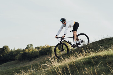 Obraz premium Professional Cyclist Descends a Slope on His Mountain Bike, Sportsman Going Down from Hill on Bicycle, Copy Space
