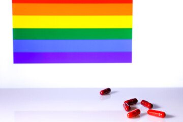Red capsules and rainbow flag in the background