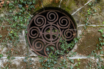 A Round window with bars in a historic stone tomb.