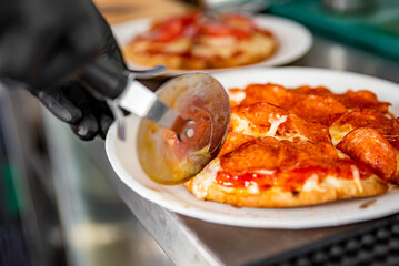 chef hand with cutter cutting mini pita pizza to pieces at pizzeria