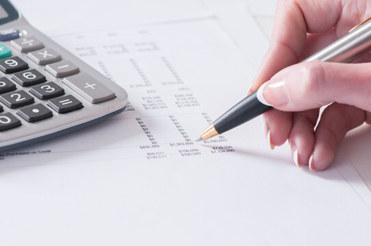 Spreadsheet With Hand Holding Pen And Calculator In Business Stock Balance Sheet