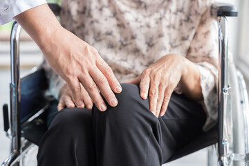 Doctor, patient knee and wheelchair. Doctor taking care knee of elderly asian woman on wheelchair at the hospital. People and health care concept
