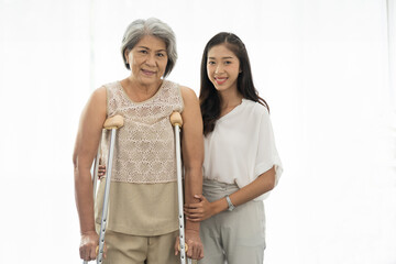 Old woman, patient and crutches. Young asian woman taking care elderly woman patient by careful with crutches nursing home. Health care concept