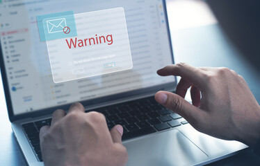 Blocking spam e-mail, warning pop-up for phishing mail, network security concept. Business man working on laptop computer at home with warning window on screen - obrazy, fototapety, plakaty