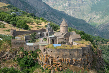 Armenia. Tatev, 9th century Armenian Apostolic Monastery, tree and mountains in the background in...