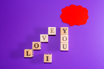 Message I love you spelled in wooden blocks with cloud. copy space,indoors shot.Purple,veri peri background.