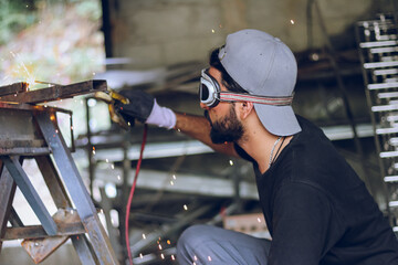 Fototapeta na wymiar Professional worker Welding metal at workshop with electric welding rod