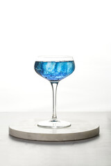 Dark blue drink in a vintage glass for sparkling wine - pea flower tea or blue curacao sirup cocktail, back lighting