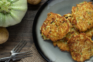 gebratene Reibekuchen aus Zucchini und Kartoffel auf Tisch aus Holz
