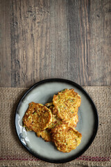 gebratene Reibekuchen aus Zucchini und Kartoffel auf Tisch aus Holz