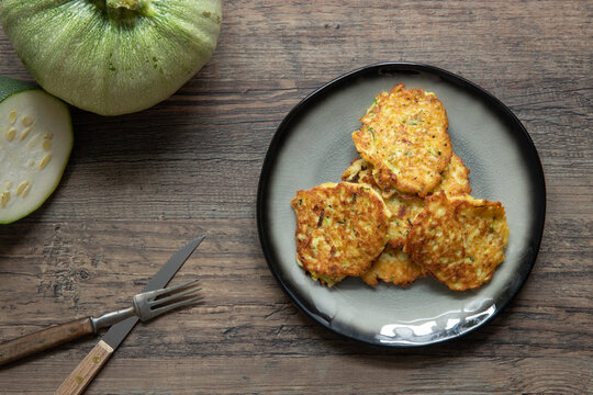 gebratene Reibekuchen aus Zucchini und Kartoffel auf Tisch aus Holz