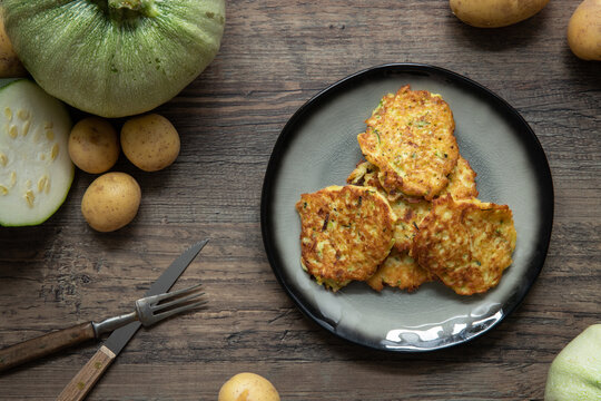 gebratene Reibekuchen aus Zucchini und Kartoffel auf Tisch aus Holz