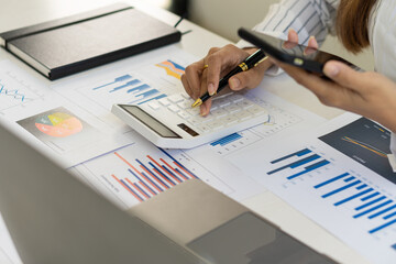 A businessman holding a smartphone working on project statistics on the device is ready. Graph...