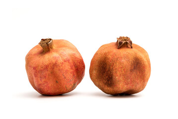 Two expired dried and spoiled pomegranates isolated on white background.