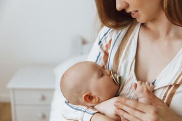 Loving mother takes care of her newborn baby at home. Portrait of a happy mother holding a sleeping baby in her arms