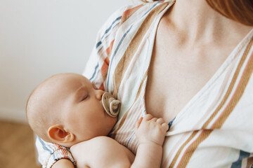 Loving mother takes care of her newborn baby at home. Portrait of a happy mother holding a sleeping baby in her arms