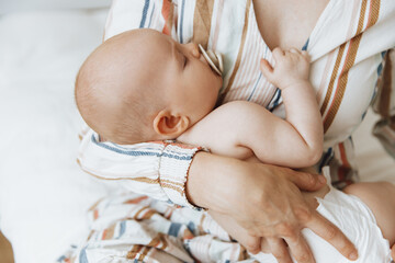 Loving mother takes care of her newborn baby at home. Portrait of a happy mother holding a sleeping...