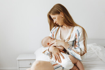 mother is holding her newborn baby. A mother is breastfeeding her child. Family at home