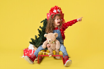 Girl with new year gifts on yellow background for copy
