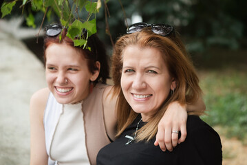 Naklejka premium Happy woman smiling after serious talk with teenage daughter, now both are happy and have good strong relationship again and trust each other, focus on mom