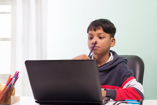 Boy using laptop and doing homework  in the  living room