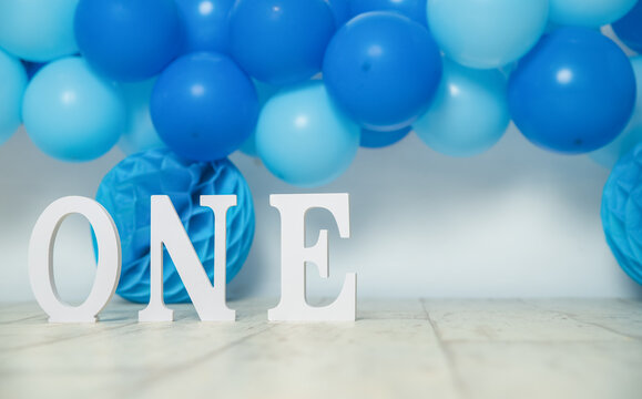 sliver, blue and white decoration for a 1st birthday cake smash studio photo shoot with balloons, paper decor, cake and topper