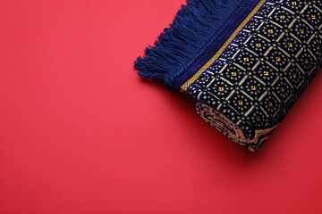 Muslim prayer rug on red background, top view. Space for text