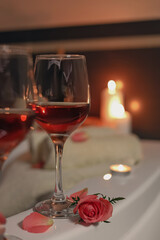 Wine in glasses and rose on edge of bath indoors, closeup. Romantic atmosphere