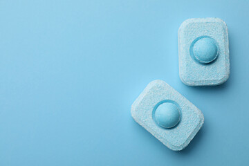 Water softener tablets on light blue background, flat lay. Space for text