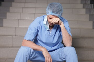 Exhausted doctor sitting on stairs in hospital
