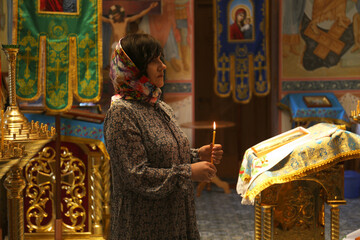 Mature woman holding burning candle in church