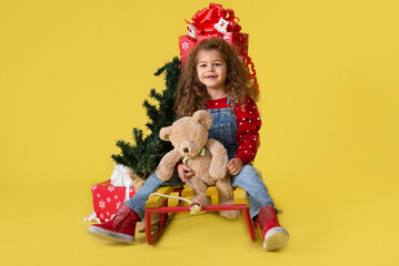 Girl with new year gifts on yellow background for copy