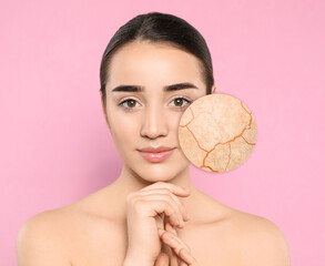 Young woman with facial dry skin problem on pink background