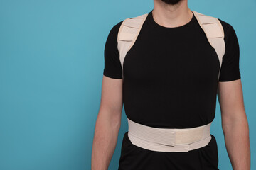 Closeup view of man with orthopedic corset on blue background. Space for text