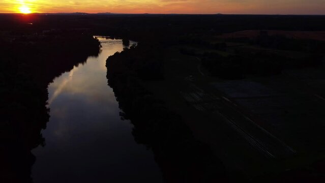 Aerial pull over Catawba River in South Carolina with fiery sunset reflected in water.