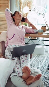 Vertical shot of a smiling girl enjoying herself at home in pajamas while talking on the phone with a friends