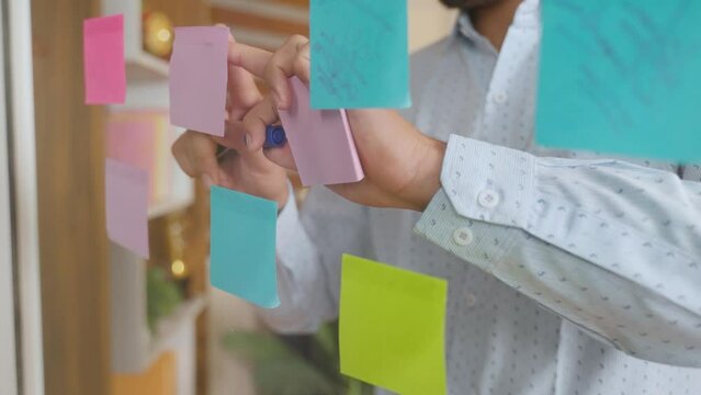 close up shot of young businessman busy planning by pasting sticky notes while working at office - concept of entrepreneur, brainstorming and analysis skills.