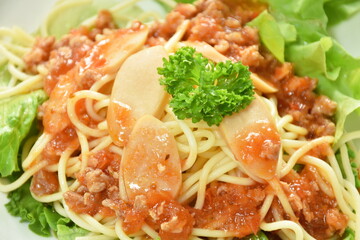 spaghetti topping slice sausage dressing fried chop pork and slice tomato in ketchup sauce with vegetableon plate   