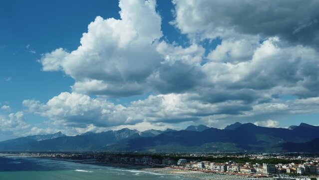 Aerial pull from the beautiful city of Viareggio on the versilian coast of Italy with dramatic cloudscape over mountains.