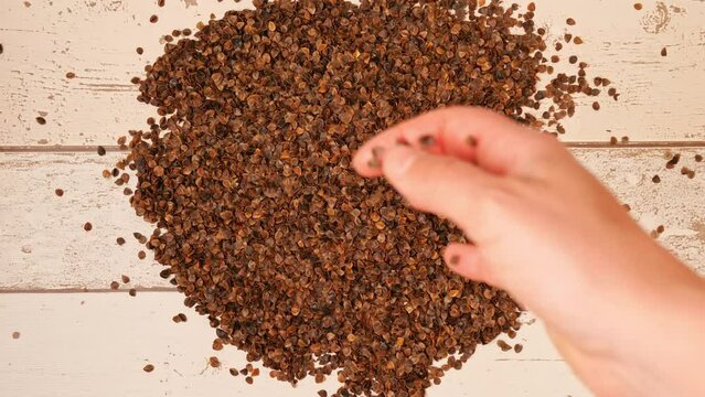 Slow motion top view video of a female hand dropping buckwheat husks down on a pile
